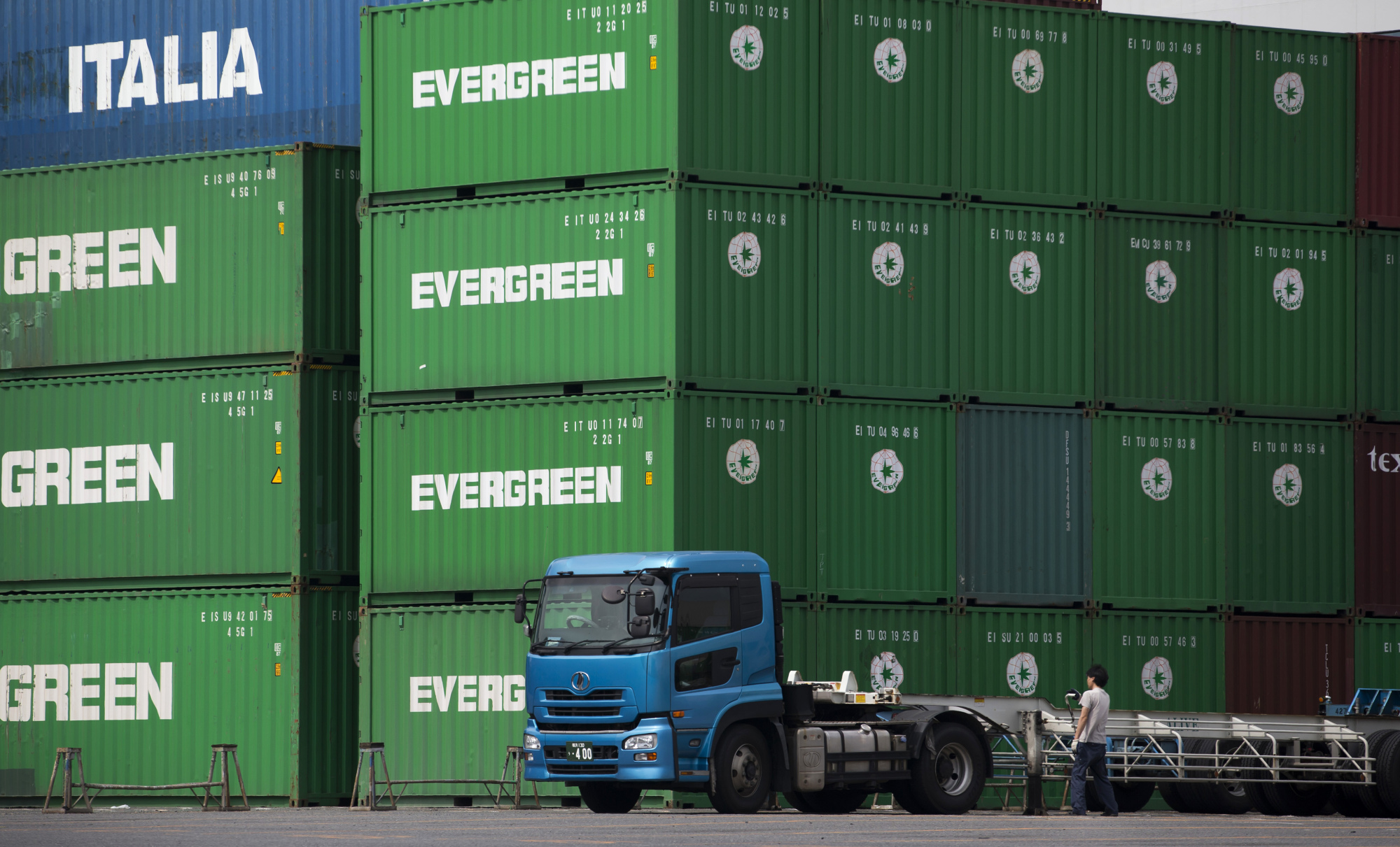 A worker stands next to a truck at a shipping terminal in Tokyo, Japan, on Wednesday, Aug. 10, 2016. Photographer: Tomohiro Ohsumi/Bloomberg